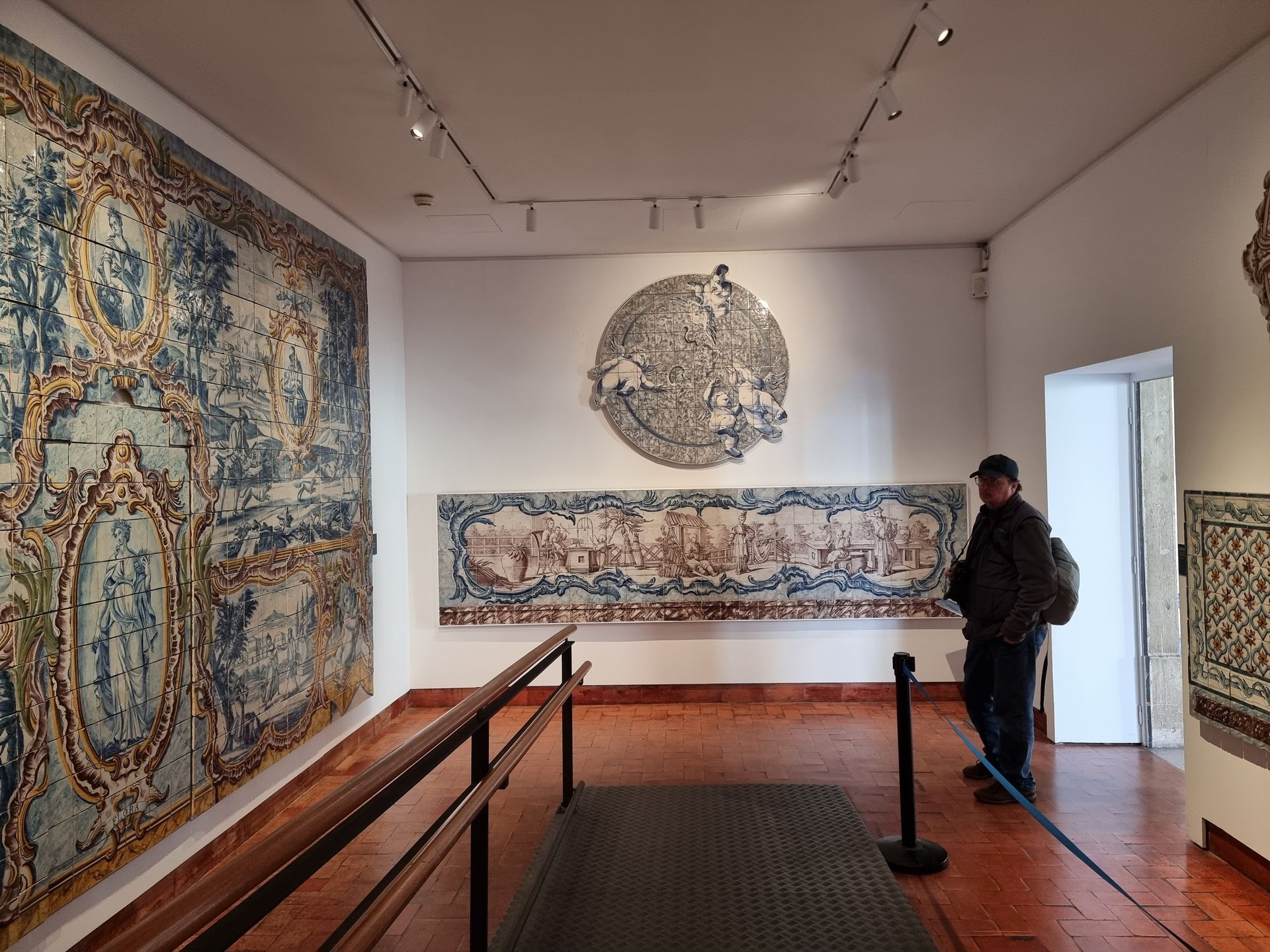 A man is standing in front of a tile panel in National Tile Museum, Lisbon.