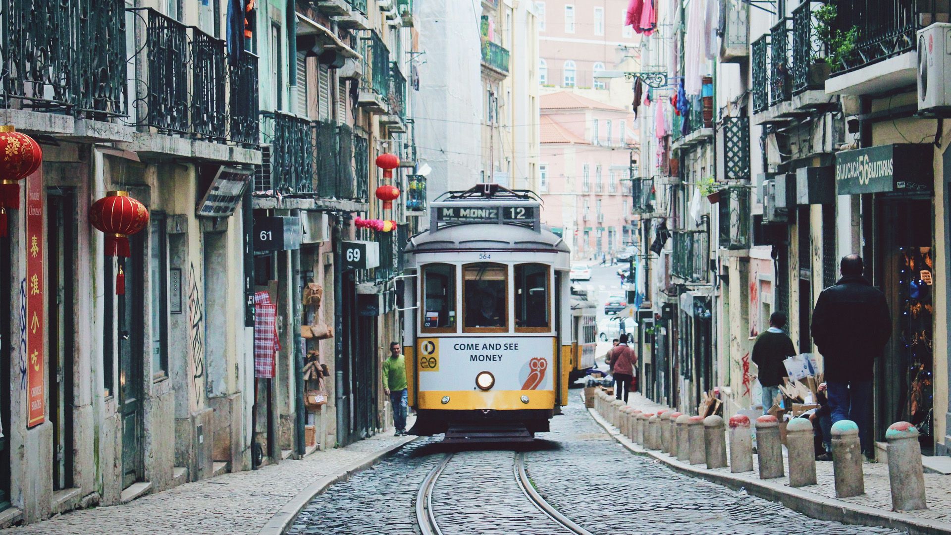 A trolley is driving down a cobblestone street in Lisbon.