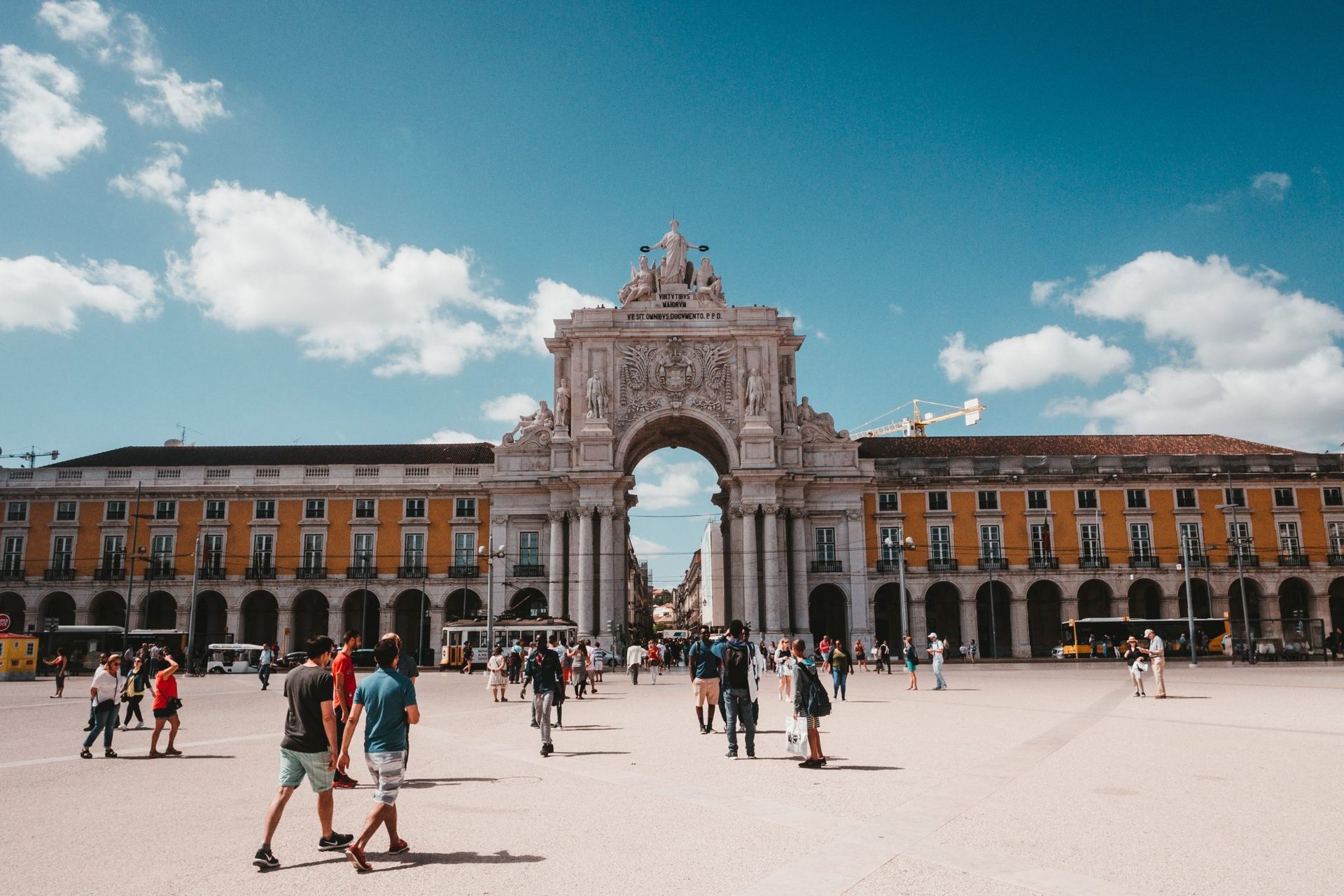 A group of people are walking in a Praça do Comércio.