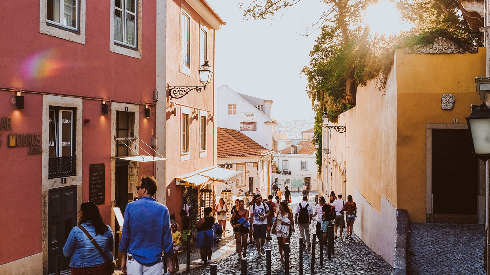 A group of people are walking down a cobblestone street in Alfama.