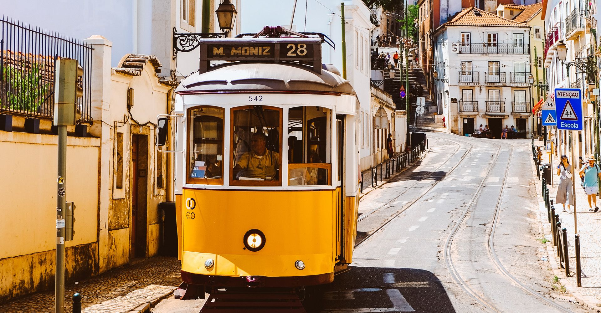 A Lisbon Tram is driving down a city street.