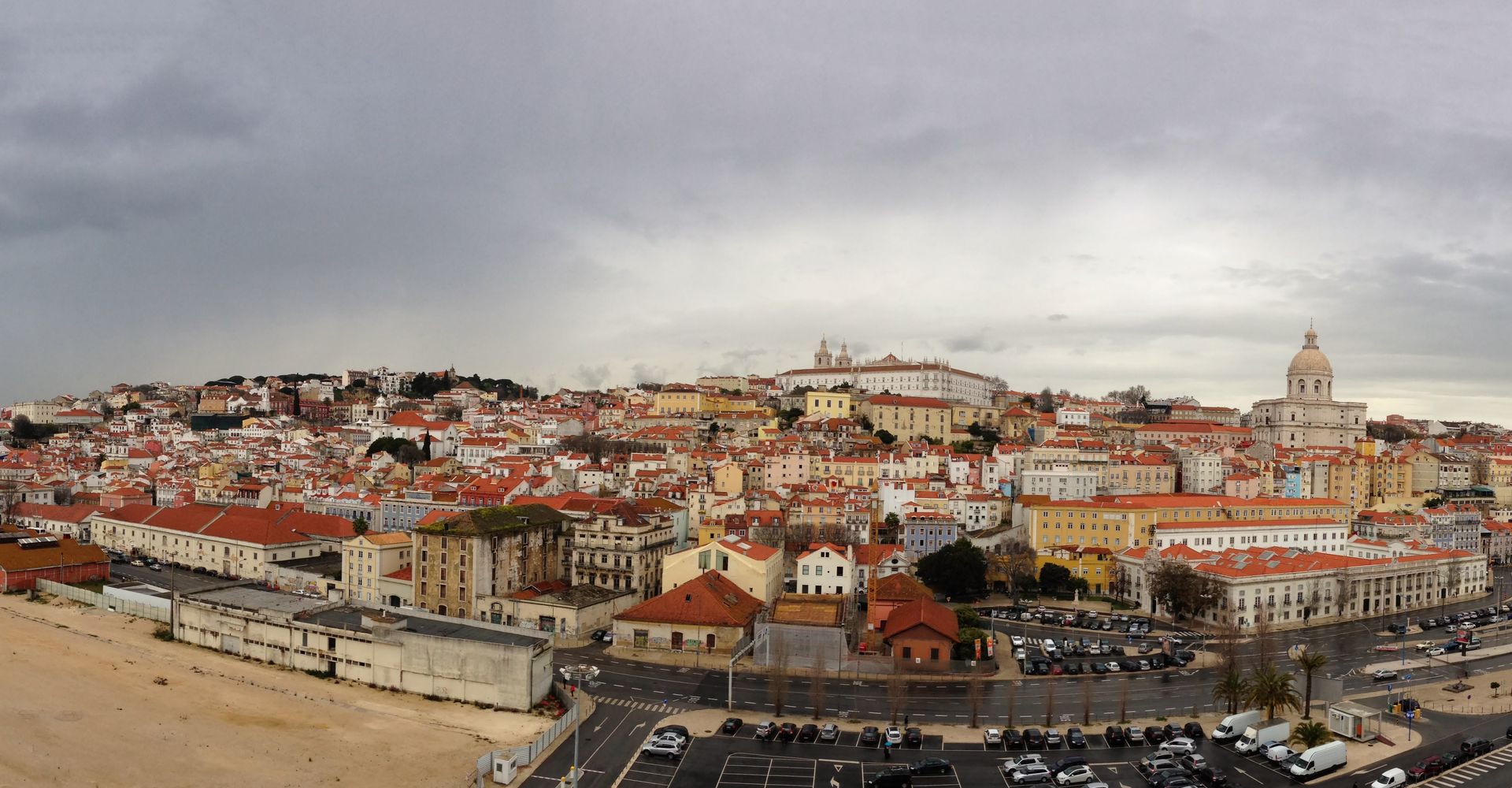 An aerial view of São Vicente Church and Alfama with red roofs on a cloudy day.
