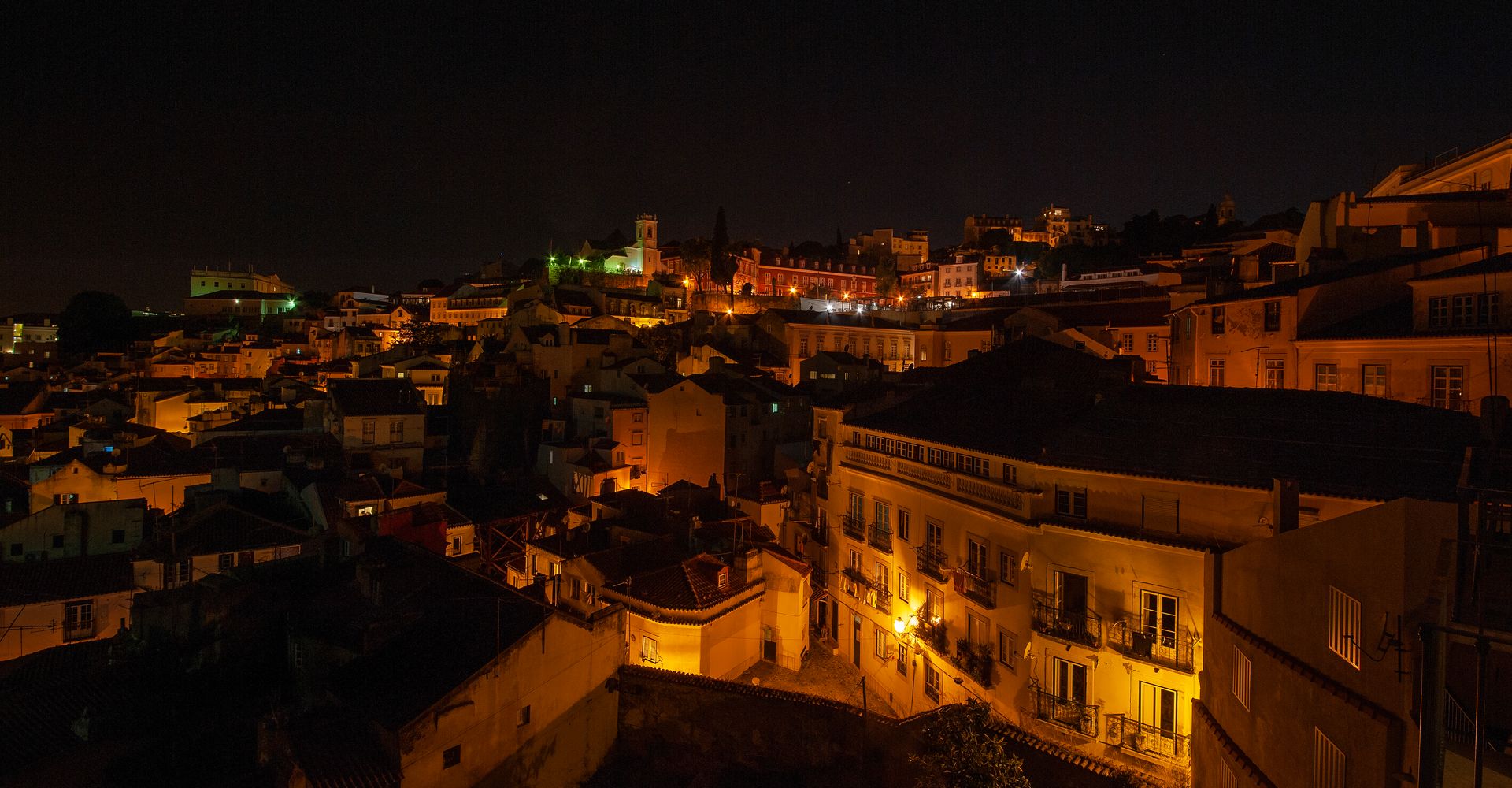 An aerial view of Lisbon at night with lots of buildings lit up.