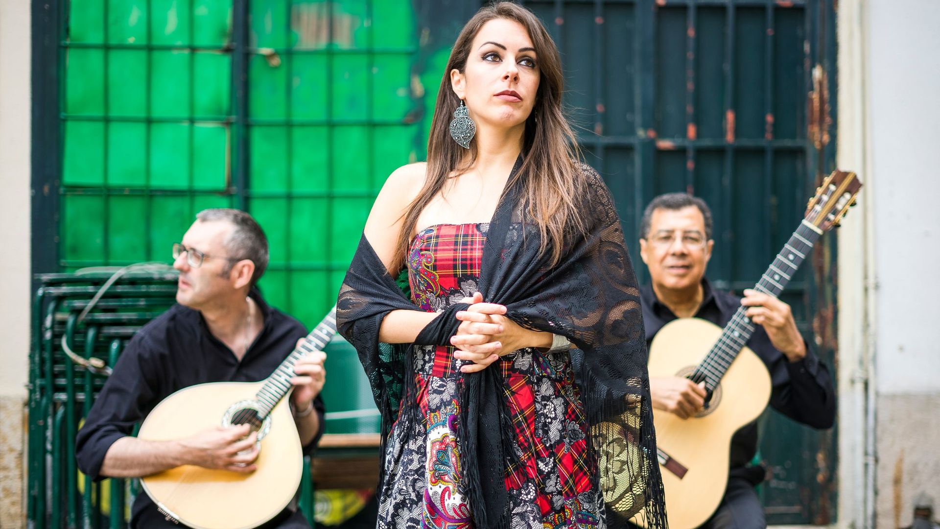 A woman singing is standing next to two men playing guitars.
